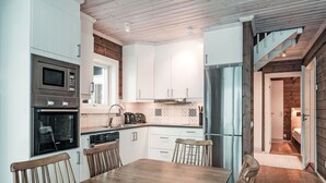 Una cocina moderna con armarios blancos, electrodomésticos de acero inoxidable y una mesa de comedor de madera con sillas.