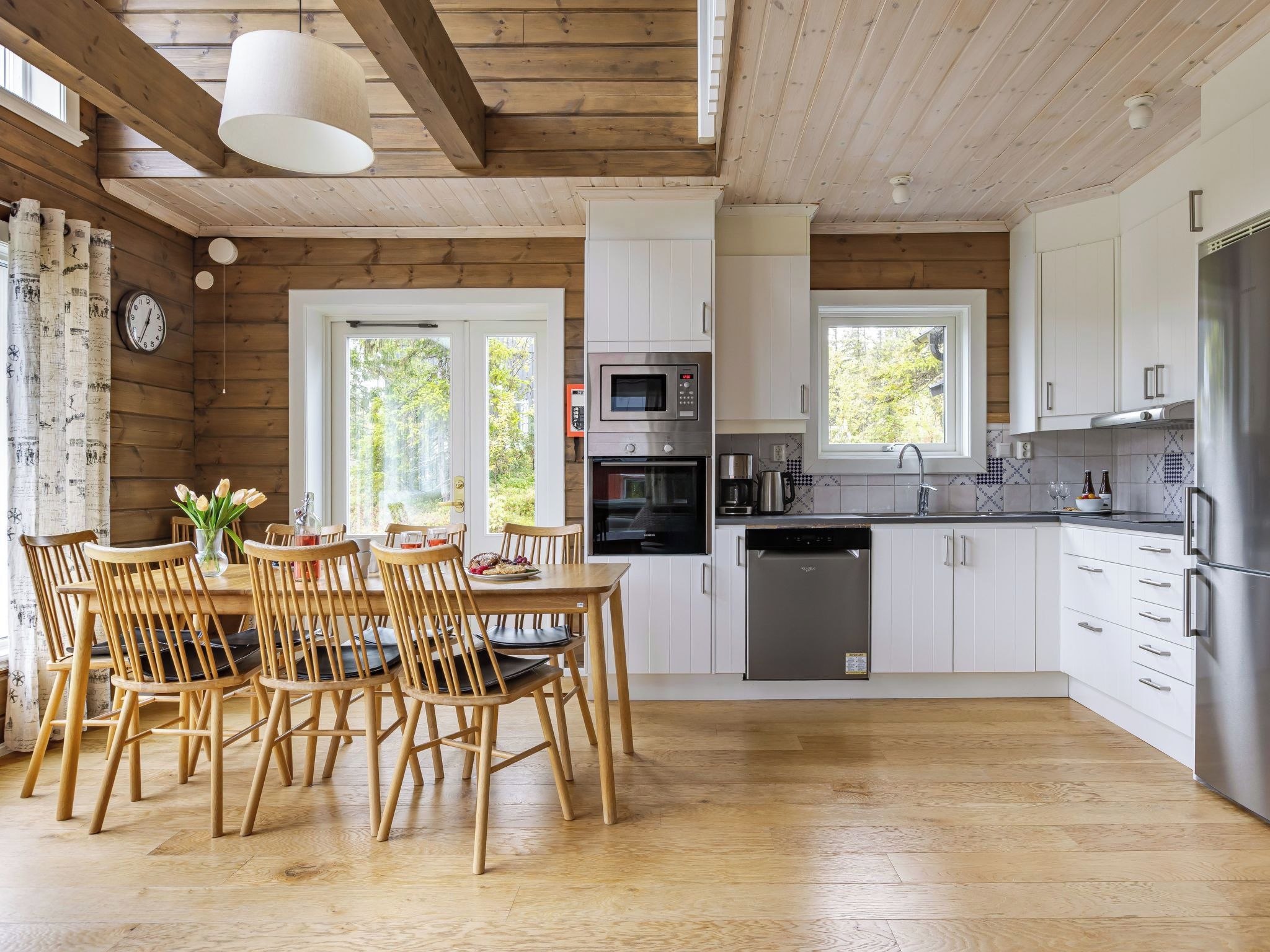 Une cuisine moderne avec un plancher en bois, des armoires blanches et des appareils électroménagers en acier inoxydable.