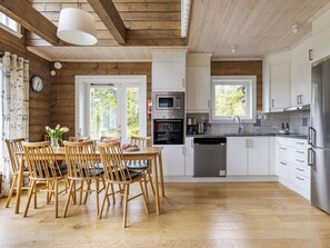 A modern kitchen with wooden floors, white cabinets, and stainless steel appliances.