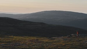 Et kuperet landskab med en person, der vandrer.