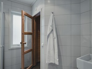 Ein Badezimmer mit weißen Fliesen, einer Holztür und einem weißen Handtuch an einem Halter.