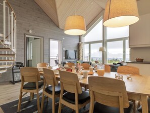 A modern dining area with a wooden table, chairs, and a television in the background. - Trillevallen 9 by Interhome (Trillevallen)