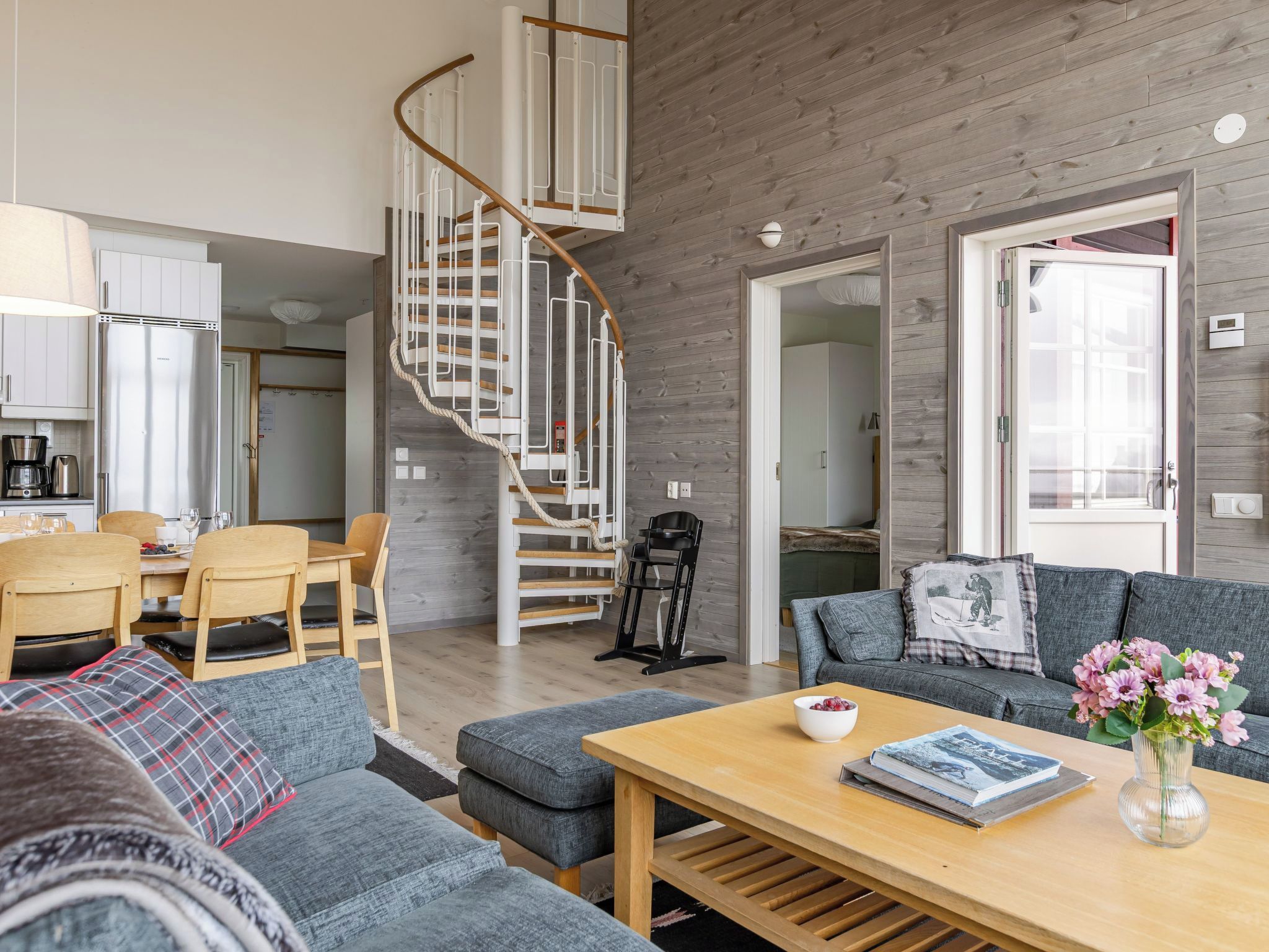 A modern living room with a staircase, a dining area, and a kitchen.