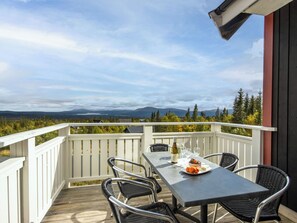 A balcony with a table set for dining, overlooking a mountainous landscape. - Trillevallen 9 by Interhome (Trillevallen)
