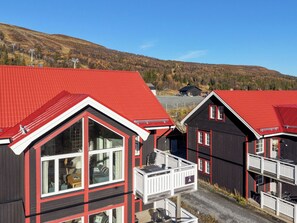 A row of cabins with red roofs and white trim, set against a backdrop of a hilly landscape.
