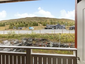 A view from a balcony overlooking a parking area with a building and a signboard. - Trillevallen 9 by Interhome (Trillevallen)