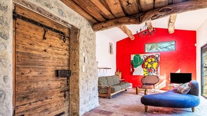 A rustic interior with a wooden door, a red wall, and a seating area with a TV. - La Bastide Neuve by Interhome (La Môle)