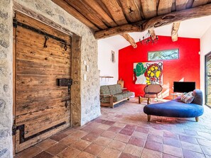 Ein rustikales Interieur mit einer Holztür, einer roten Wand und einer Sitzecke mit Fernseher.