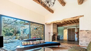 A spacious living area with a stone wall, a large window, and a view of the outdoors. - La Bastide Neuve by Interhome (La Môle)