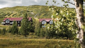 A rural setting with two buildings with red roofs, surrounded by greenery and a hill in the background. - Trillevallen 2 by Interhome (Trillevallen)