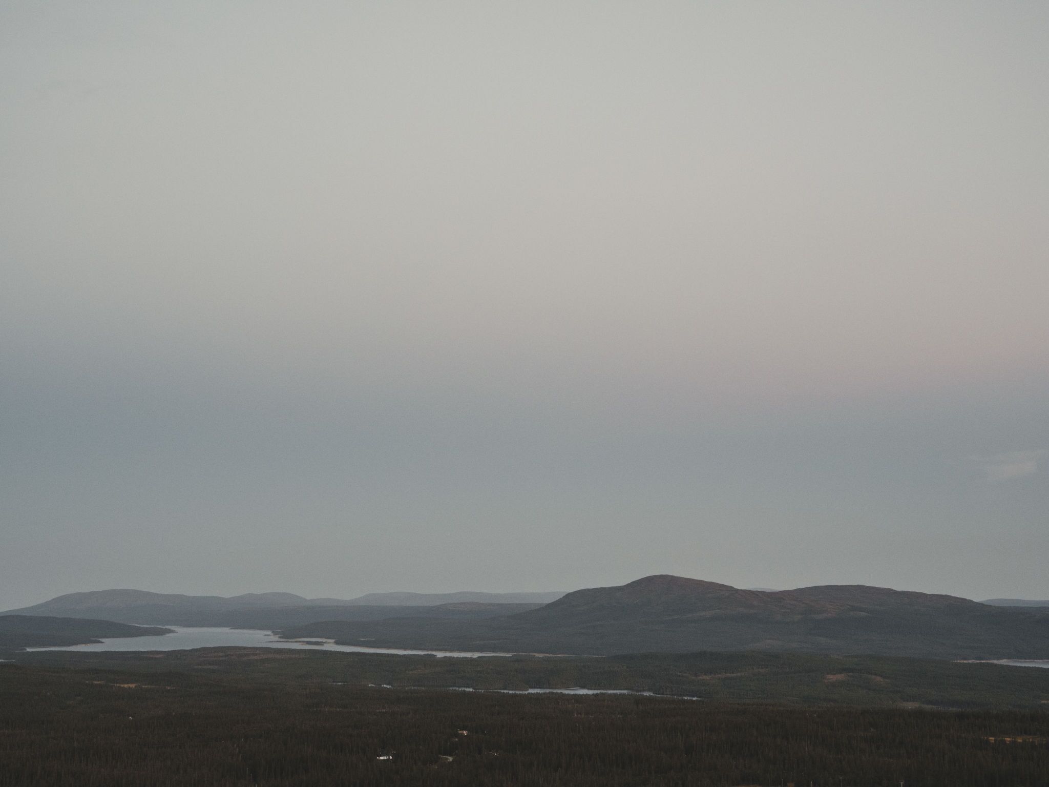 Un vaste paysage avec un lac et des montagnes à l’horizon.