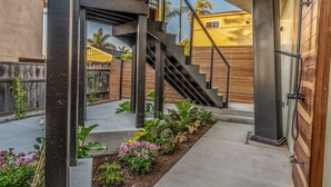A modern outdoor staircase with metal railings, a concrete landing, and a wooden fence in the background.