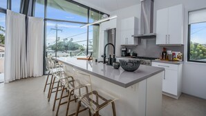 A modern kitchen with a large island, white cabinetry, and a view of the outdoors.