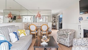 A spacious living room with a large mirror, a sofa, a coffee table, and a fireplace. - New! Bayfront 3 BD/3BA Retreat with Private Patio! (San Diego)