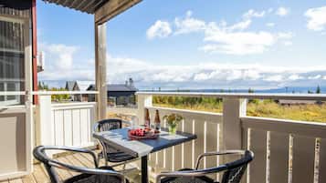 A balcony with a table and chairs, overlooking a scenic landscape.