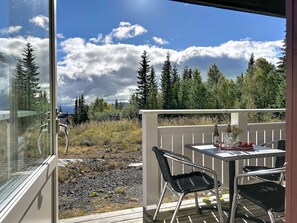 A balcony with a table and chairs, overlooking a forested area with a clear sky. - Trillevallen 1 by Interhome (Trillevallen)