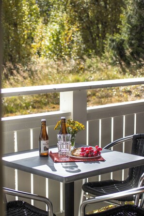 A table set outdoors with a bottle, glass, flowers, and a plate of grapes. - Trillevallen 1 by Interhome (Trillevallen)
