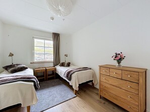 A bedroom with two beds, a dresser, a window with curtains, and a ceiling light fixture. - Trillevallen 1 by Interhome (Trillevallen)