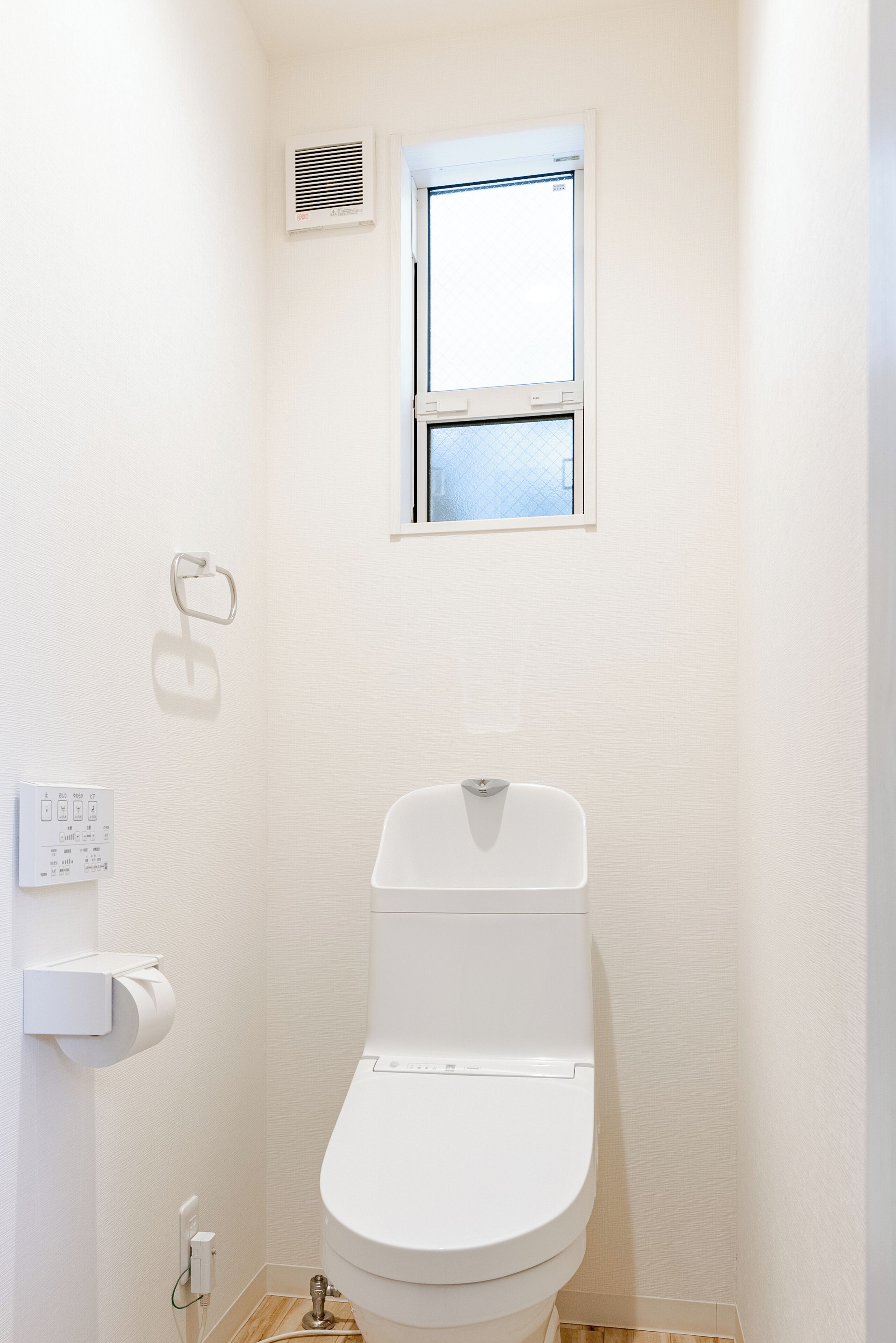 Un baño pequeño y blanco con un inodoro, una ventana y un respiradero de pared.