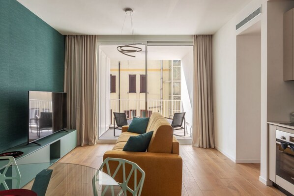 A modern living room with a sofa, TV, and dining area.