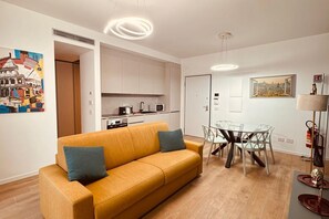 Un salon moderne comprenant un canapé, une table à manger avec des chaises, un coin cuisine et des œuvres d’art accrochées aux murs.
