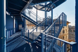 A blue metal staircase leading to an upper level, with a clear view of the surrounding buildings.