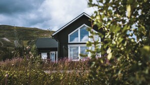 A modern house with a sloped roof, large windows, and surrounded by natural vegetation. - Trillevallen Fjällripan by Interhome (Trillevallen)