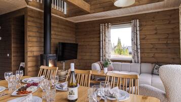 Un intérieur en bois avec une table à manger dressée pour le repas, un canapé et une cheminée.
