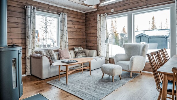A cozy cabin interior with a sofa, armchair, and dining table. - Trillevallen Fjällripan by Interhome (Trillevallen)