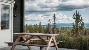A wooden picnic table on a deck with a view of mountains and a lake. - Trillevallen Fjällripan by Interhome (Trillevallen)