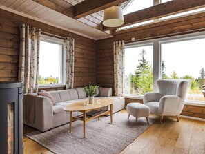 Un interior de cabaña acogedor, con sofá, sillón y chimenea.