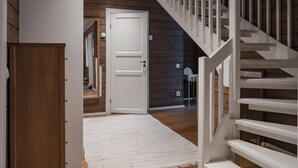A wooden interior with a white staircase, a white door, and a white rug. - Trillevallen Fjällripan by Interhome (Trillevallen)