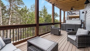 Una terraza techada con mobiliario de mimbre, un jacuzzi y vistas a árboles.