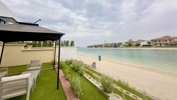 Eine Terrasse mit Gartenmöbeln, einem Pool und Blick auf Strand und Gebäude.