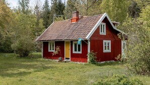 A red wooden house with a sloped roof, a chimney, and a flag.