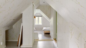 A room with sloped ceilings, a bed, a window, and a door.
