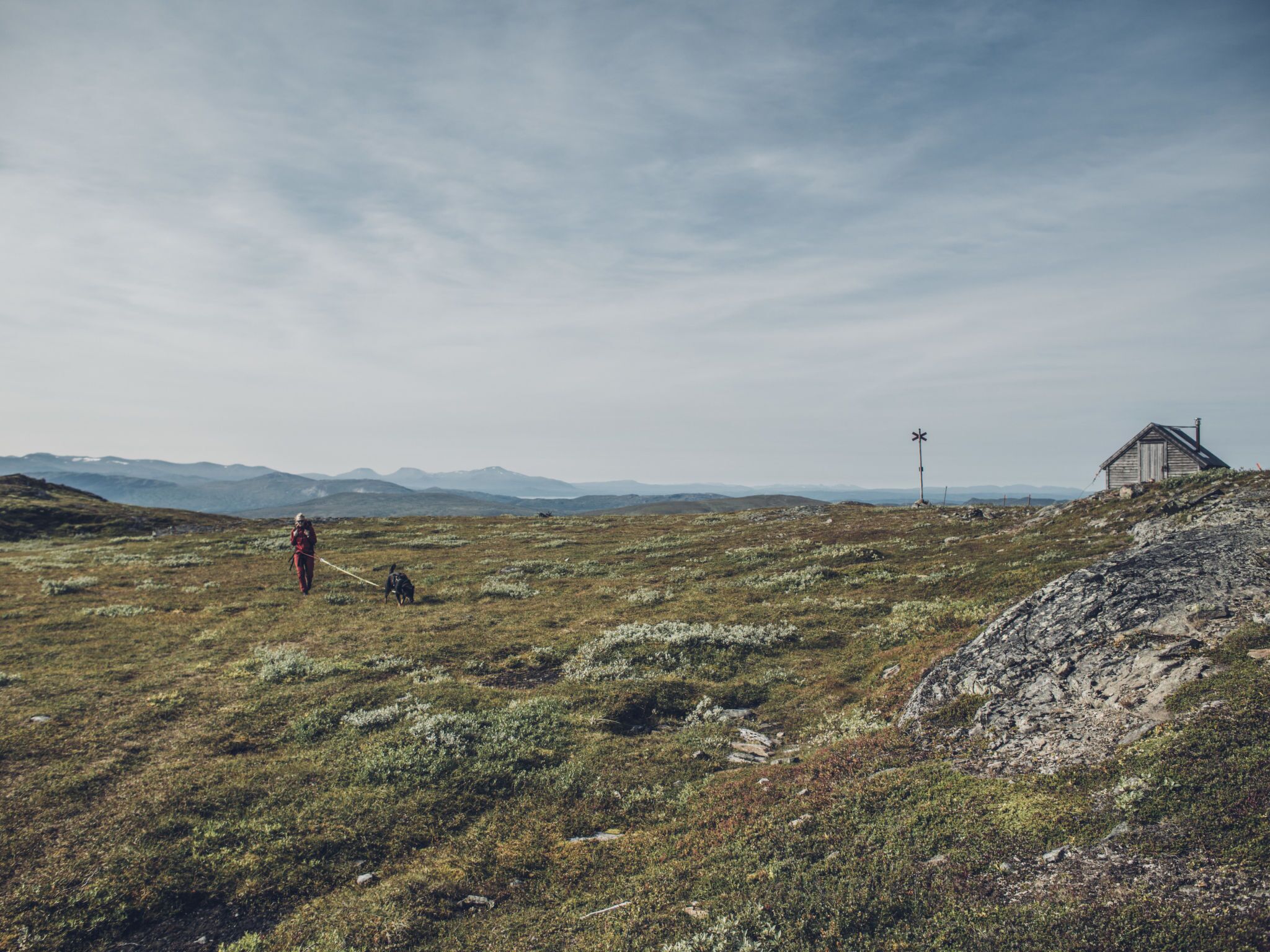 A remote, rugged landscape with a small wooden cabin and a windmill in the distance.