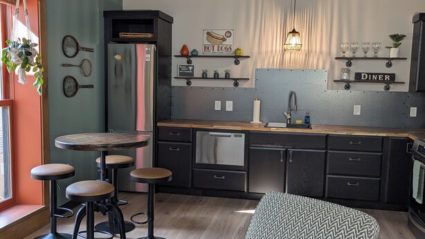 Une cuisine moderne avec un coin repas, des tabourets de bar, un réfrigérateur et un panneau indiquant « Diner ».