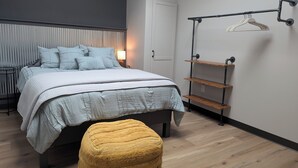 Une chambre à coucher moderne avec un lit, une table de chevet, une lampe et une étagère suspendue.