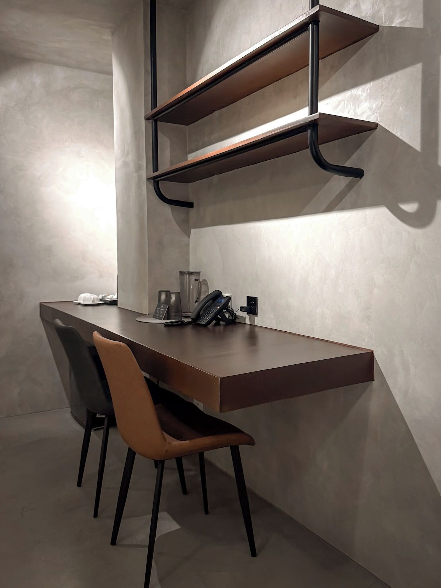 A modern office space with a desk, two chairs, and a telephone.