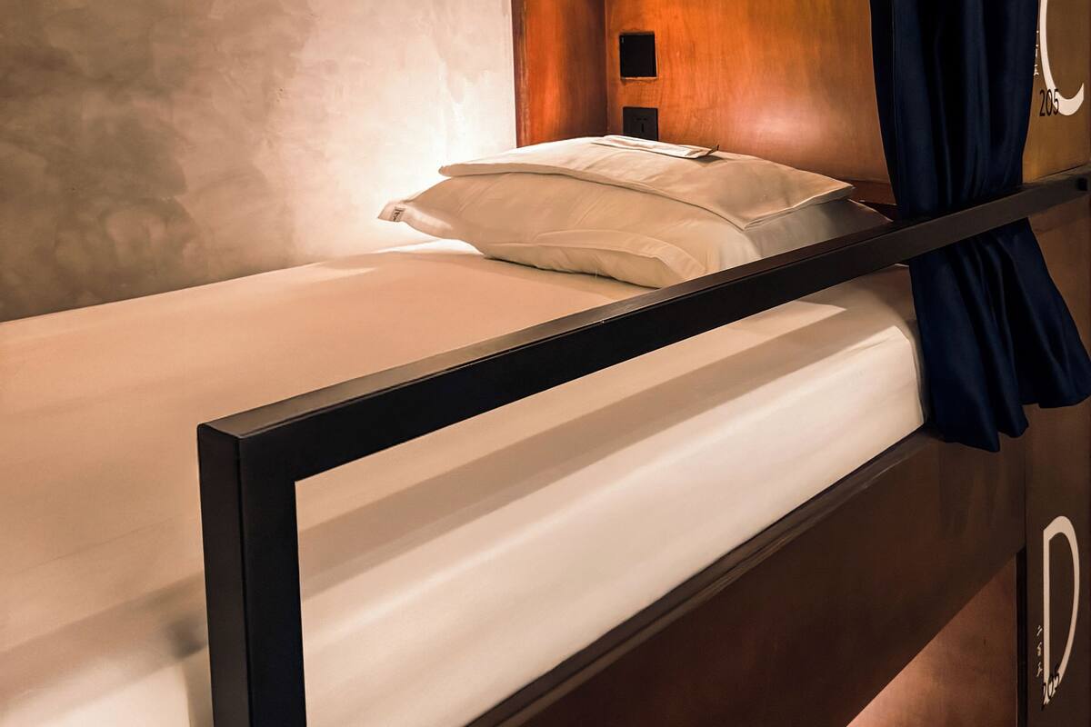 A bunk bed with a headboard, a bedside lamp, and a curtain.