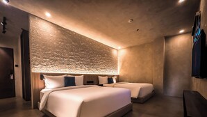 A modern hotel room with two beds, a textured wall, and recessed ceiling lights. - Yamato Hostel (Pasay)