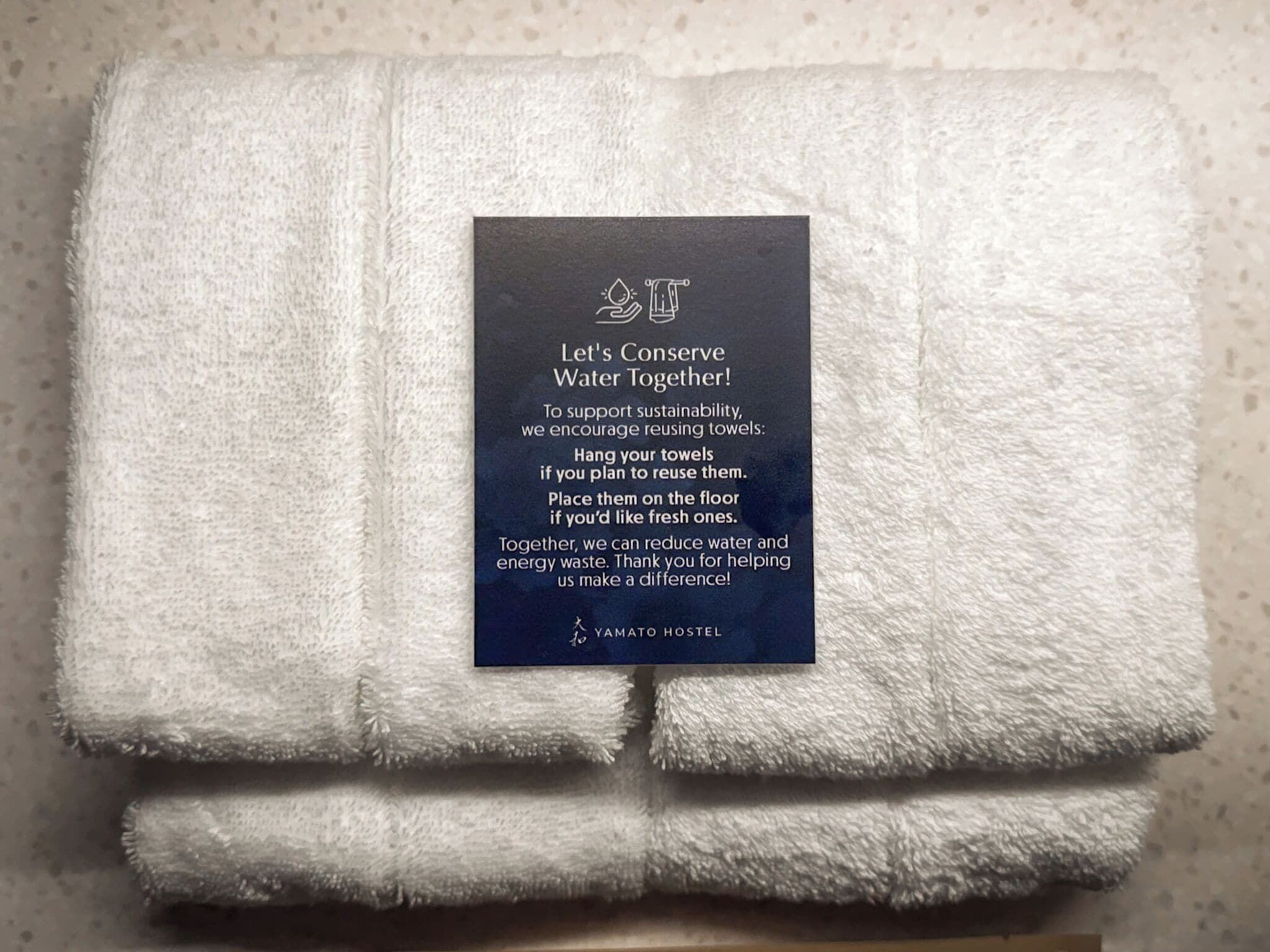 A folded white towel with a conservation message about water reuse.