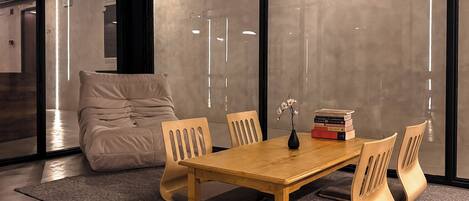 Una sala de reuniones moderna con una mesa de madera, sillas acolchadas, un jarrón con flores y libros.