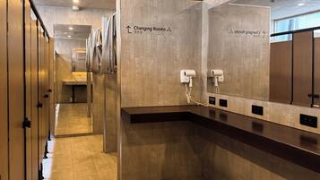 A modern changing room with mirrors, a sink, and hair dryers.
