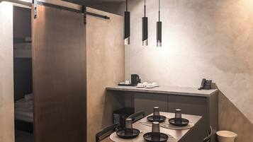 A modern dining area with a wooden table, black candle holders, and a coffee machine.