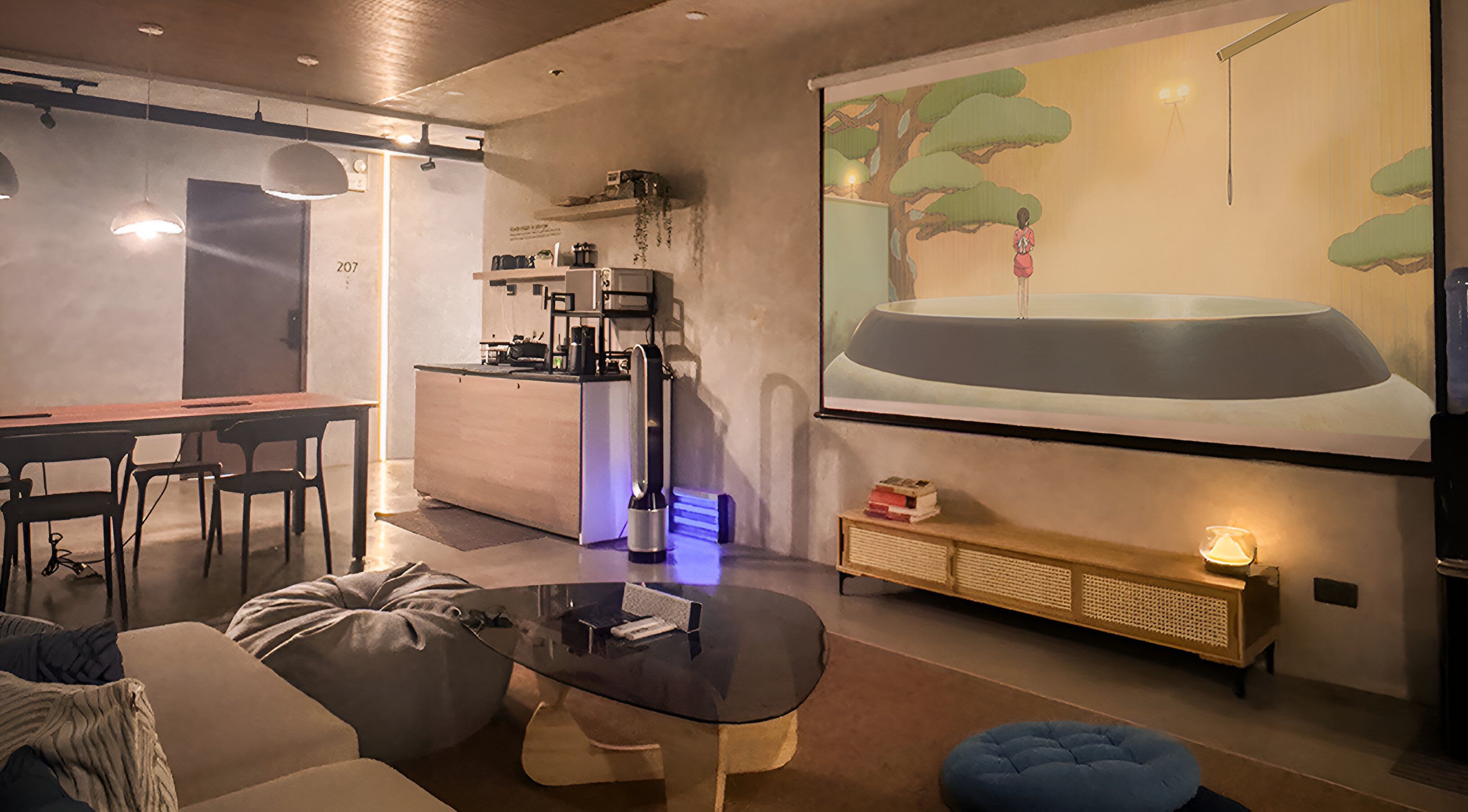 Een moderne woonkamer met een groot scherm waarop een auto, een koffieapparaat en een gezellige zithoek met een hippe zak en voetenbankje te zien zijn.