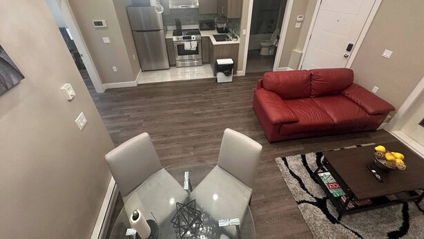 En moderne stue med et glasbord, en rød sofa og et sofabord med citroner.