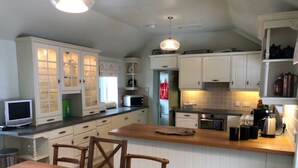 Et køkken med hvide skabe, et træspisebord og en mikroovn.