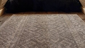 Een gezellig slaapkamer onder het dak, met schuine wanden, houten lambrisering, een bed met een kussen in de vorm van een eland, en een raam met uitzicht op een huis.